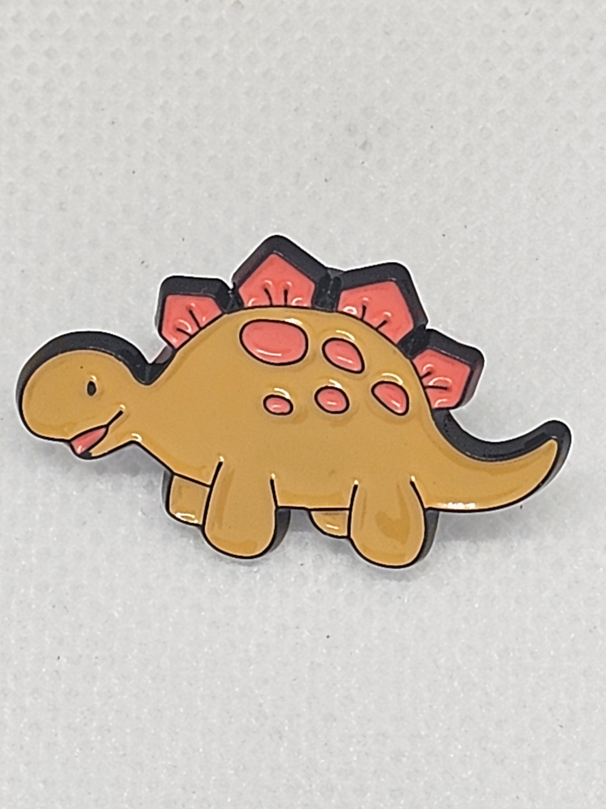 Cute dinosaur pin badge featuring a cartoon stegosaurus design in yellow and pink colors, perfect for collectors.