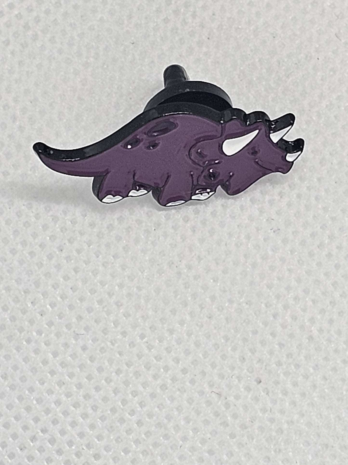 Purple triceratops enamel pin badge, perfect for dinosaur lovers as a bag or clothing accessory.