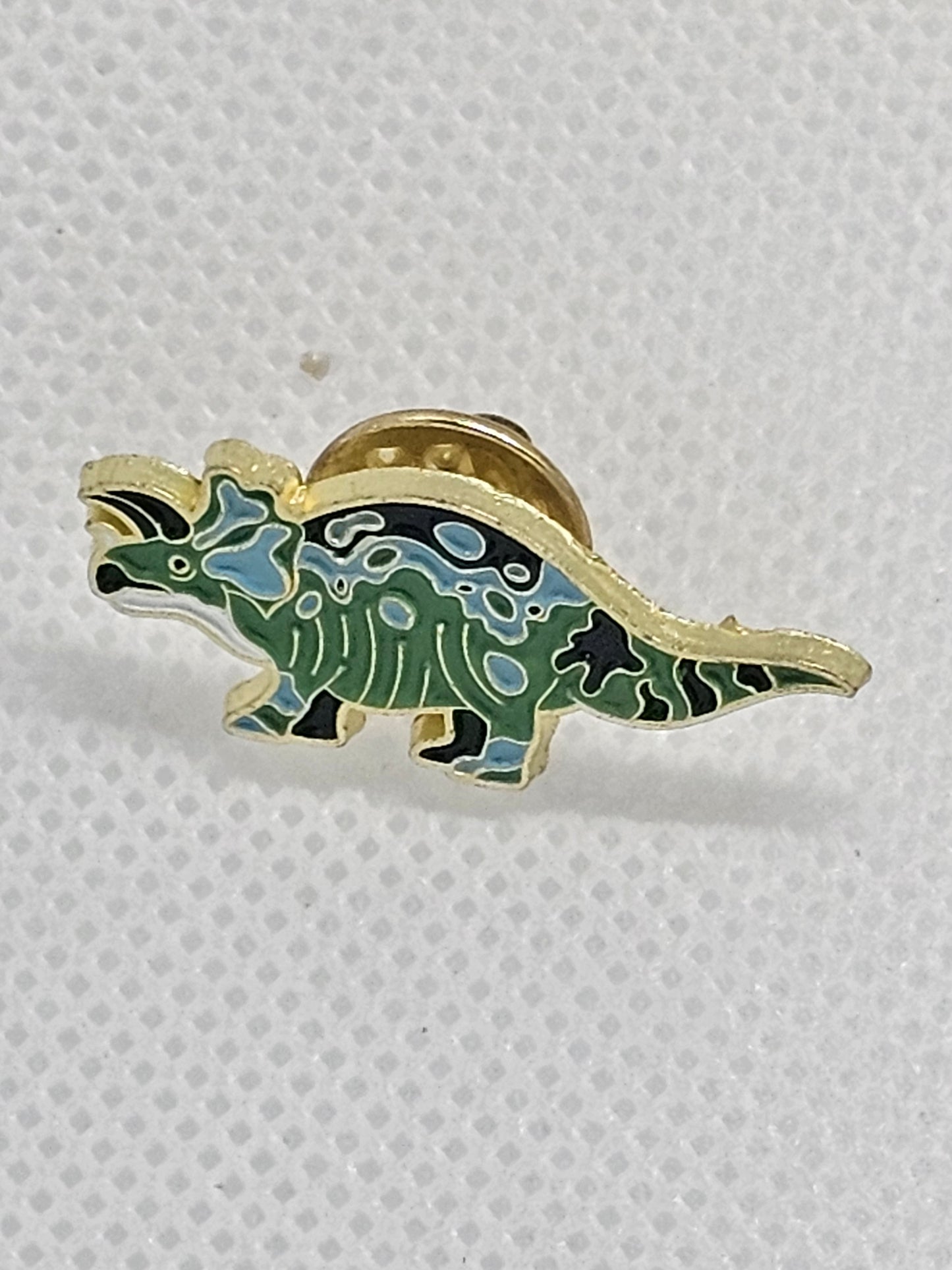 Cute green enamel dinosaur pin badge with a gold outline, perfect accessory for dinosaur lovers.