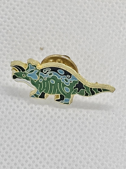 Cute green enamel dinosaur pin badge with a gold outline, perfect accessory for dinosaur lovers.