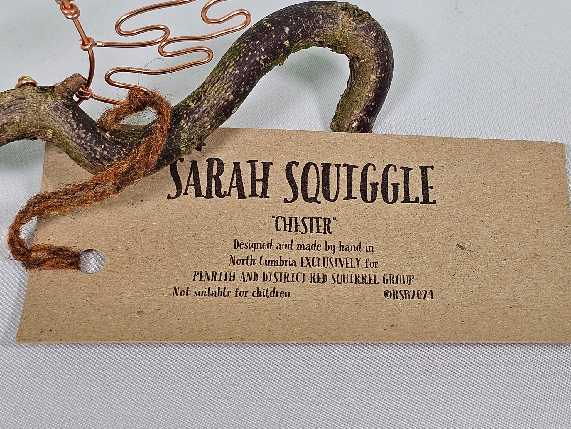Brown tag with 'Sarah Squiggle' branding on a white background