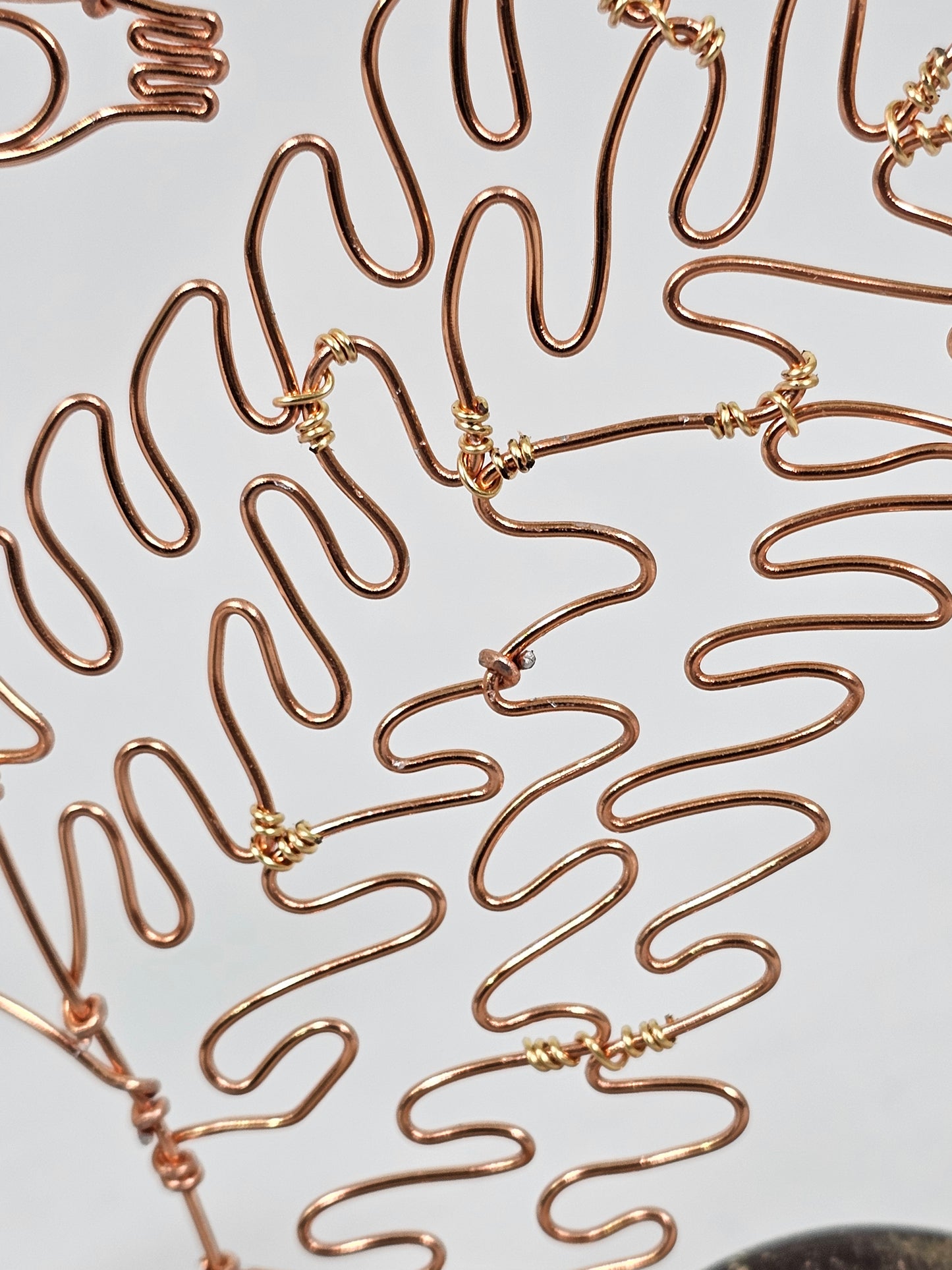 Close-up of gold wire sculptures on a white background
