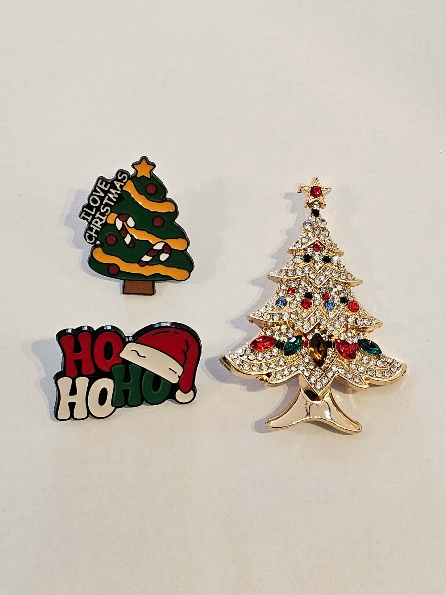 Three Christmas-themed pins on a light gray background