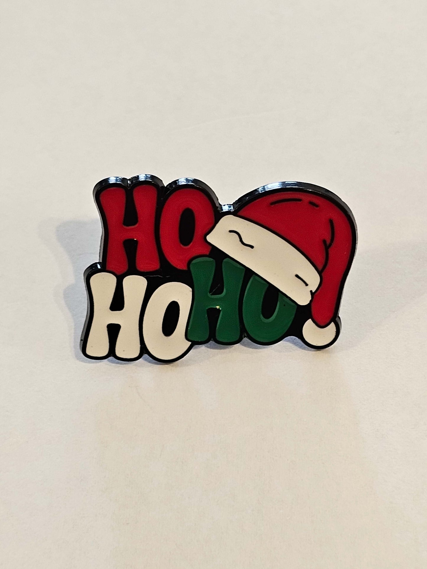 Christmas-themed badge with Santa hat and 'HO HO HO' text on a beige background