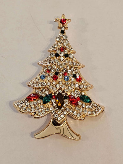 Decorative Christmas Tree shaped brooch with gemstones on a beige background