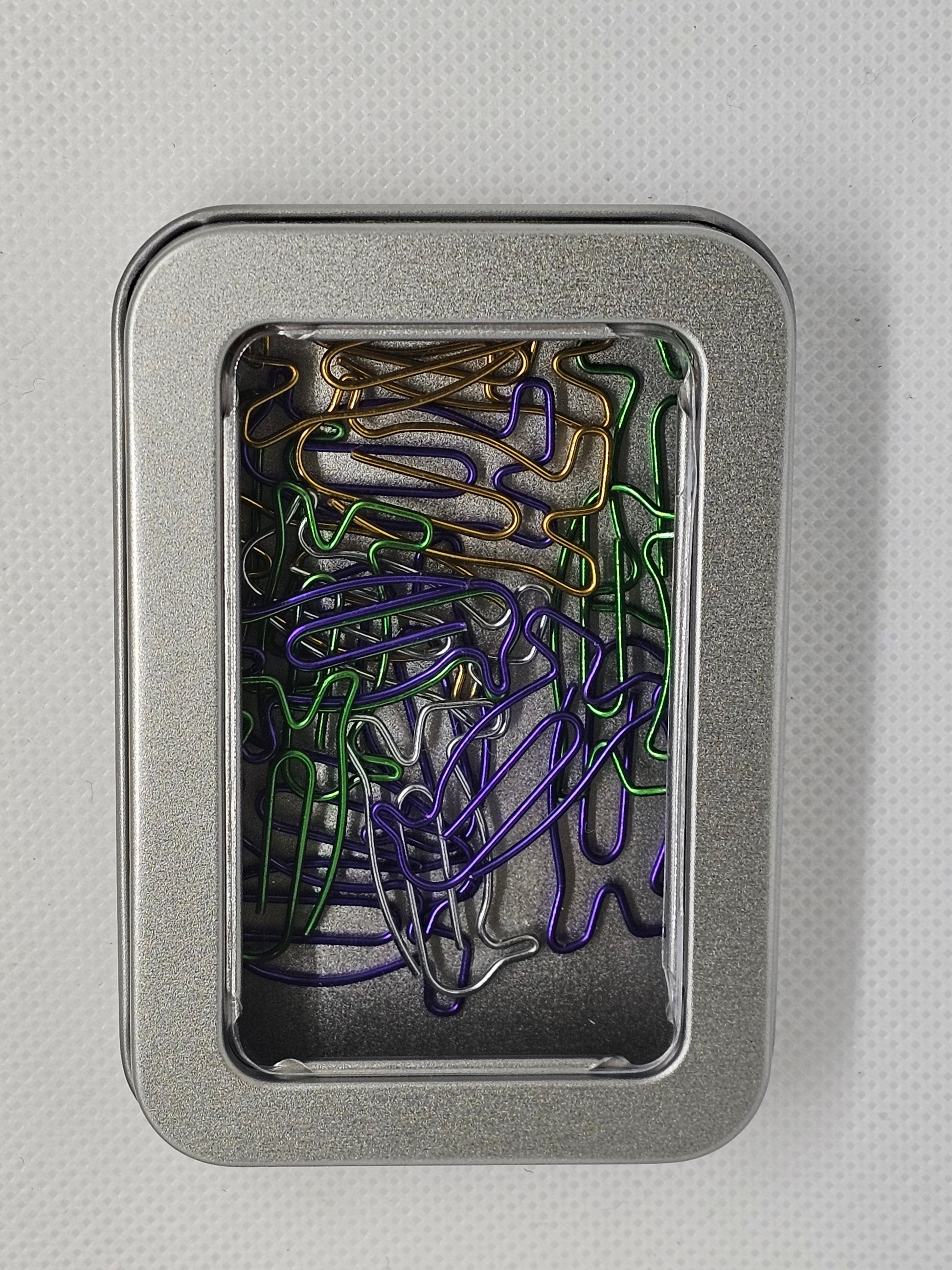 Colorful paper clips in a metal tin on a gray background