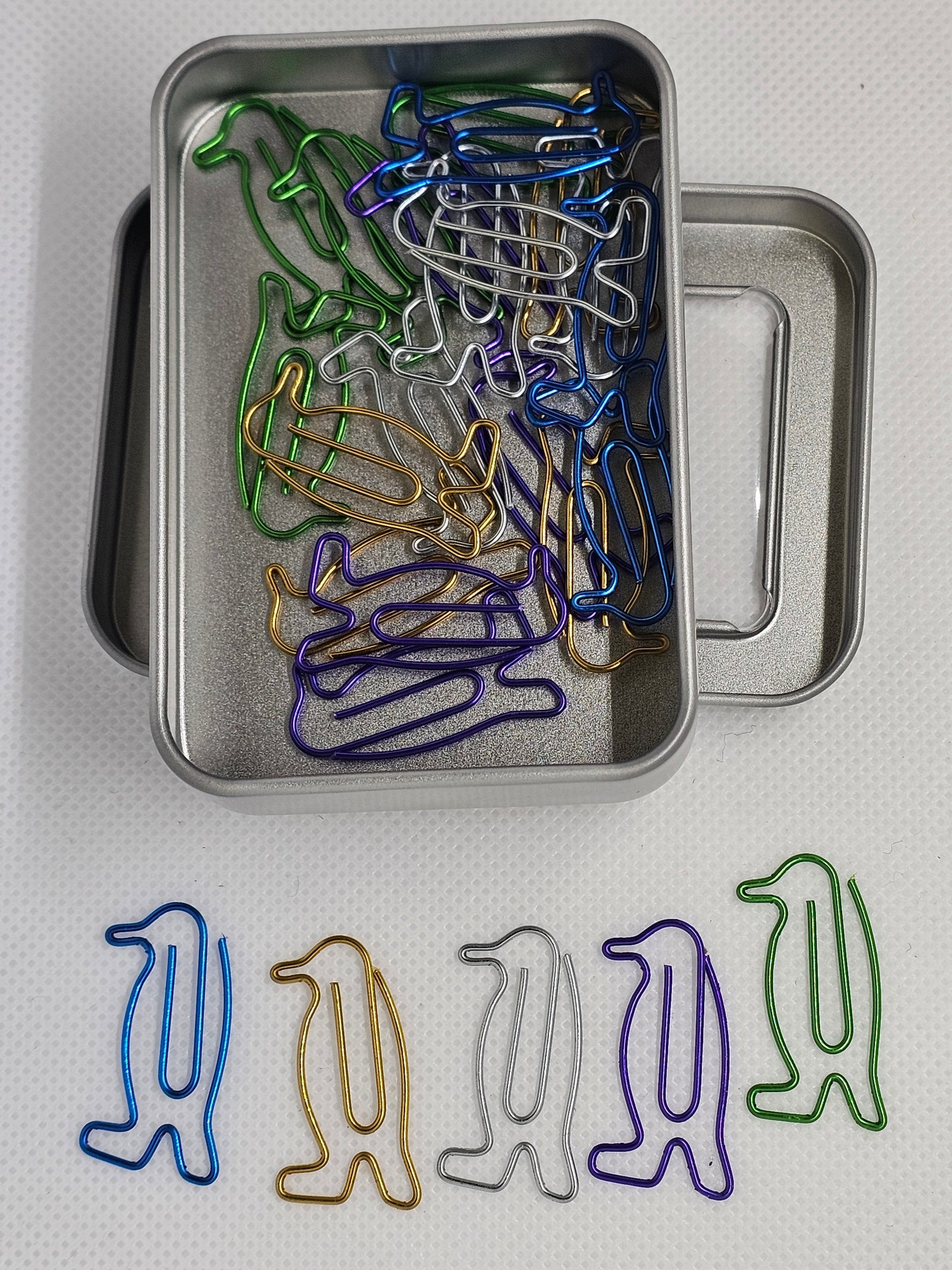 Metal tin with colorful paper clips on a white background