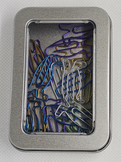 Colorful paper clips in a metal tin on a light gray background