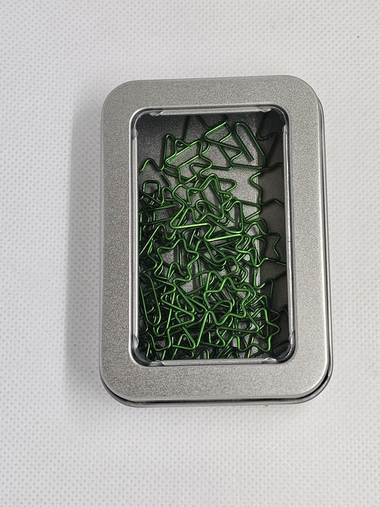 Metal tin with green paper clips on a light gray background