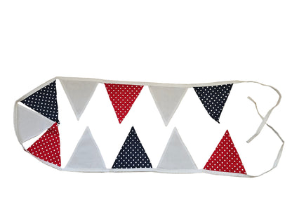 Fabric bunting with red, white, and blue polka dot triangles on a wooden surface