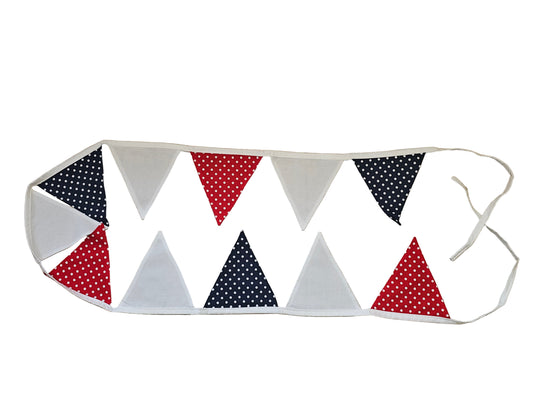 Fabric bunting with red, white, and blue polka dot triangles on a wooden surface