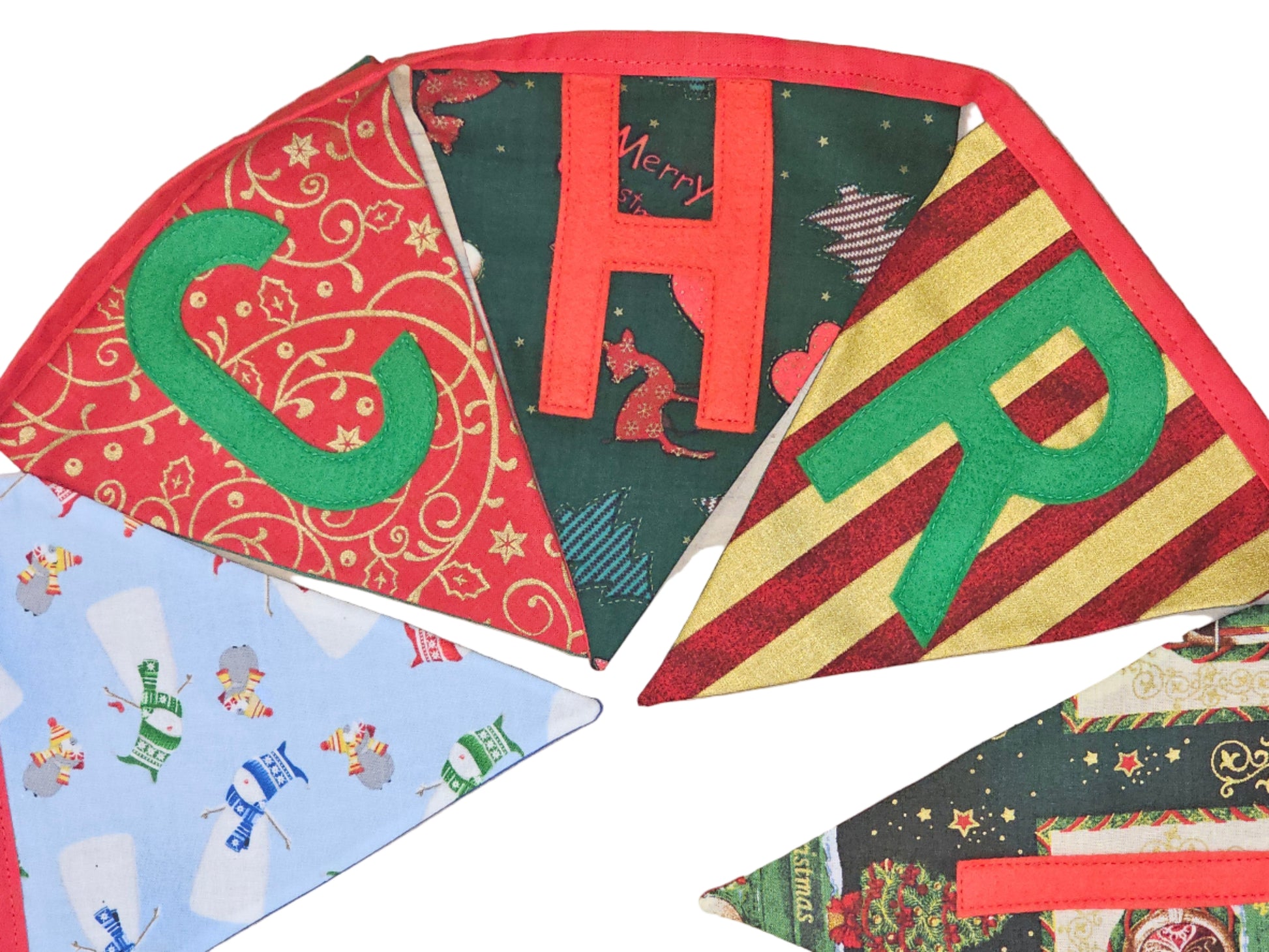 Decorative Christmas-themed fabric panels with letters spelling 'Merry Christmas' on a wooden surface.