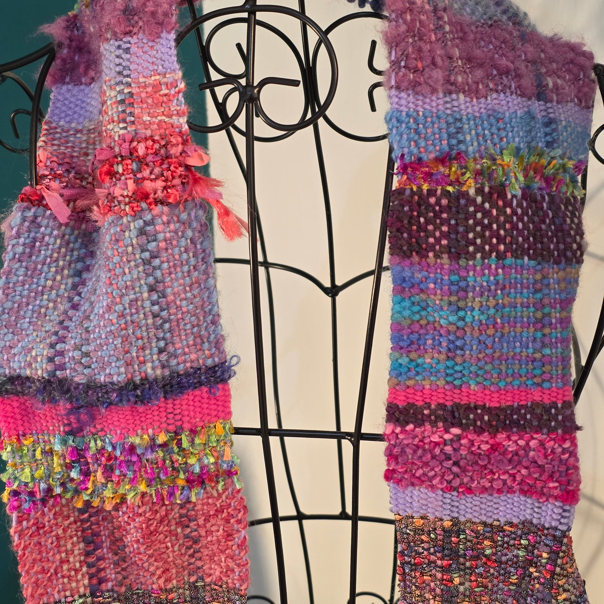 Multicolored woven scarf on a mannequin against a neutral background