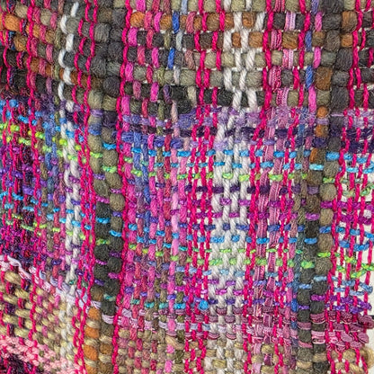 Multicolored woven rug with a pattern of pink, purple, and green on a dark background.