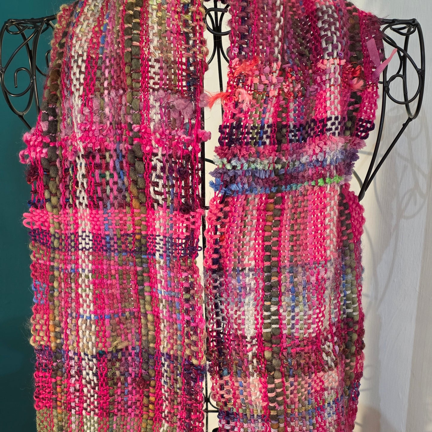 Multicolored woven fabric on a black metal stand against a white background