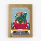 Pack of Christmas cards with a red car carrying a Christmas tree and Santa Claus, on a white background.
