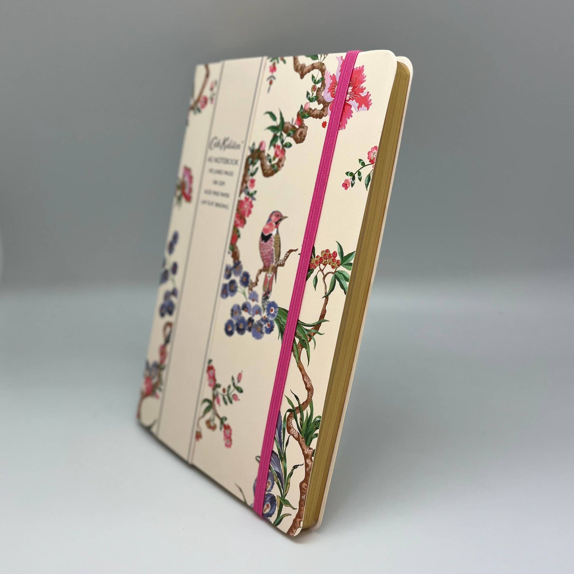 Notebook with floral and bird design on cover and pink ribbon bookmark on gray background
