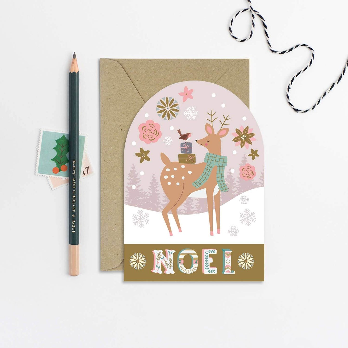 Christmas card with a deer illustration and 'Noel' text, featuring a pencil and envelope on a white background.