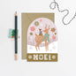 Christmas card with a deer illustration and 'Noel' text, featuring a pencil and envelope on a white background.
