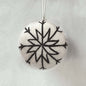 Round stone pendant with black snowflake design on a light gray background
