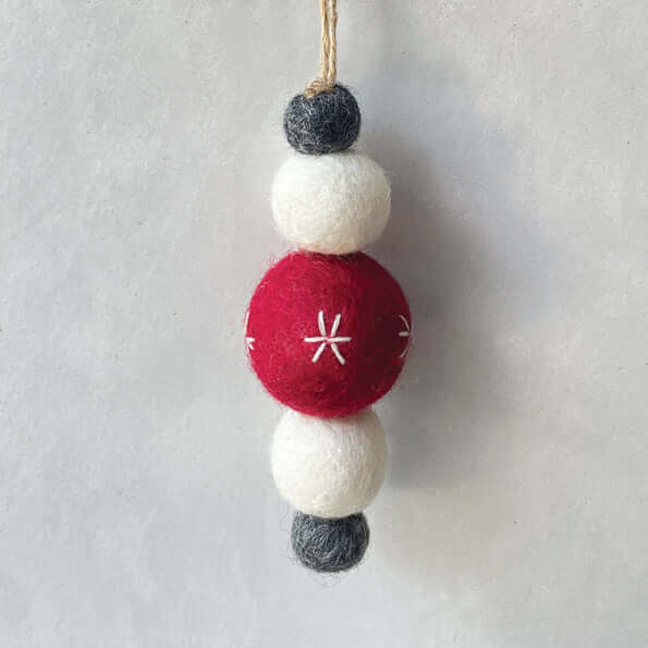 Decorative hanging ornament with red, white, and gray felt balls on a light gray background