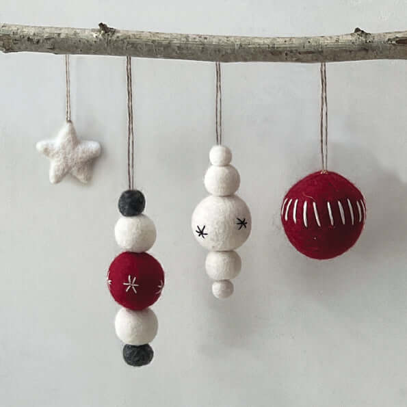 Decorative ornaments hanging from a branch on a light gray background