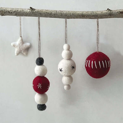 Decorative ornaments hanging from a branch on a light gray background