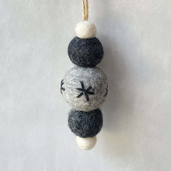 Decorative hanging ornament with felt balls on a plain background