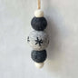 Decorative hanging ornament with felt balls on a plain background