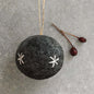 Black felt ornament with white star patterns on a gray surface