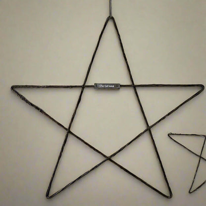 Large Metal Hanging Christmas Star - East of India on a wall, showcasing rustic handmade design with a silver plaque.