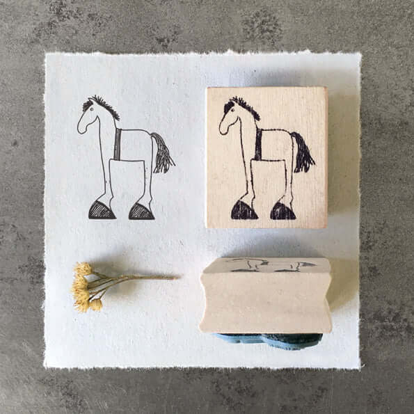 Two horse-shaped rubber stamps on a textured surface with a small yellow flower.