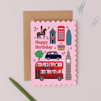 Birthday card with London-themed illustrations on a pink background, featuring a red bus, clock tower, and other elements.