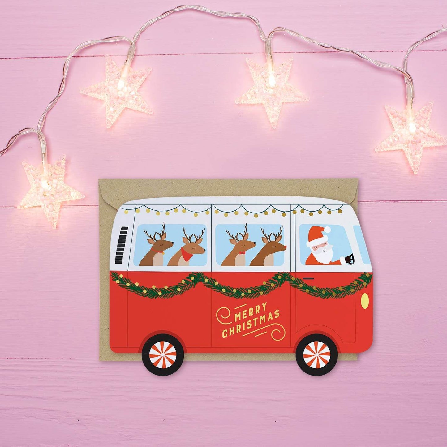 Red Christmas van card with Santa and reindeer on a pink background with string lights.