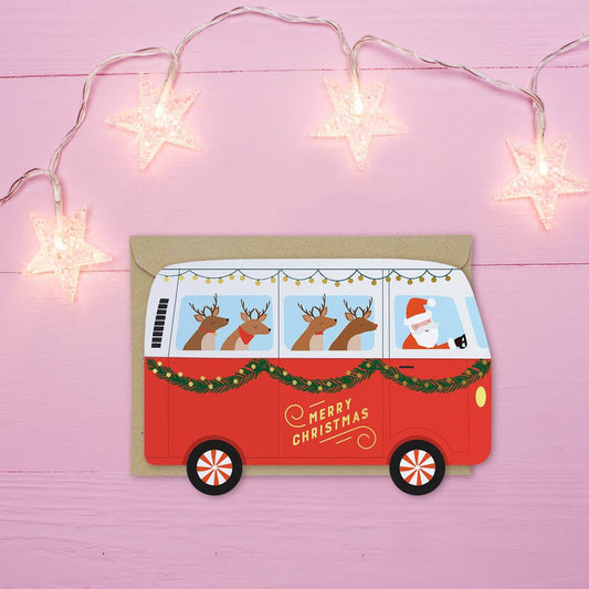 Red Christmas van card with Santa and reindeer on a pink background with string lights.