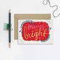 Christmas card with 'Merry and Bright' text, envelope, pencil, and decorative string on a white background