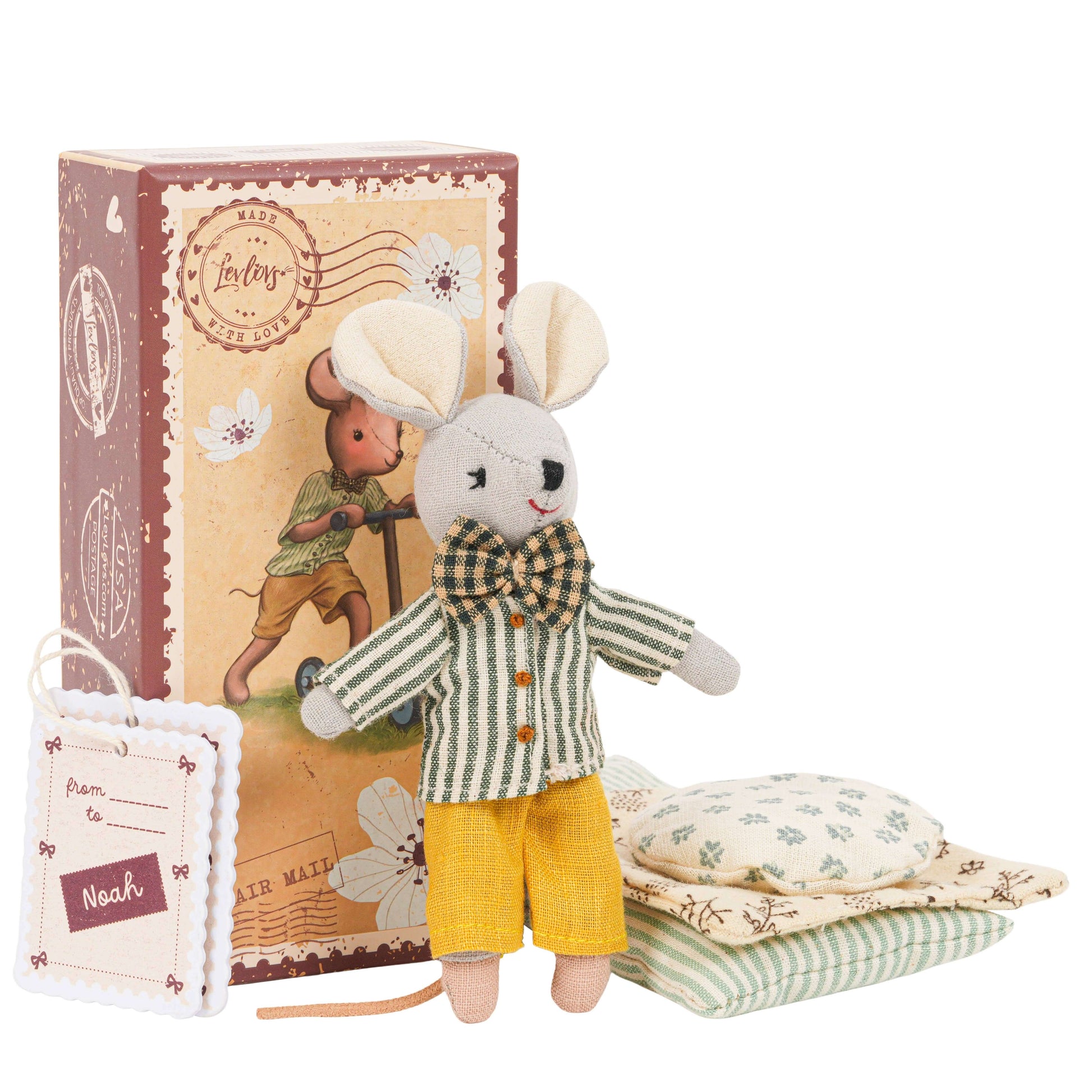 Toy mouse in a checkered shirt and yellow shorts with a box and pillows in the background