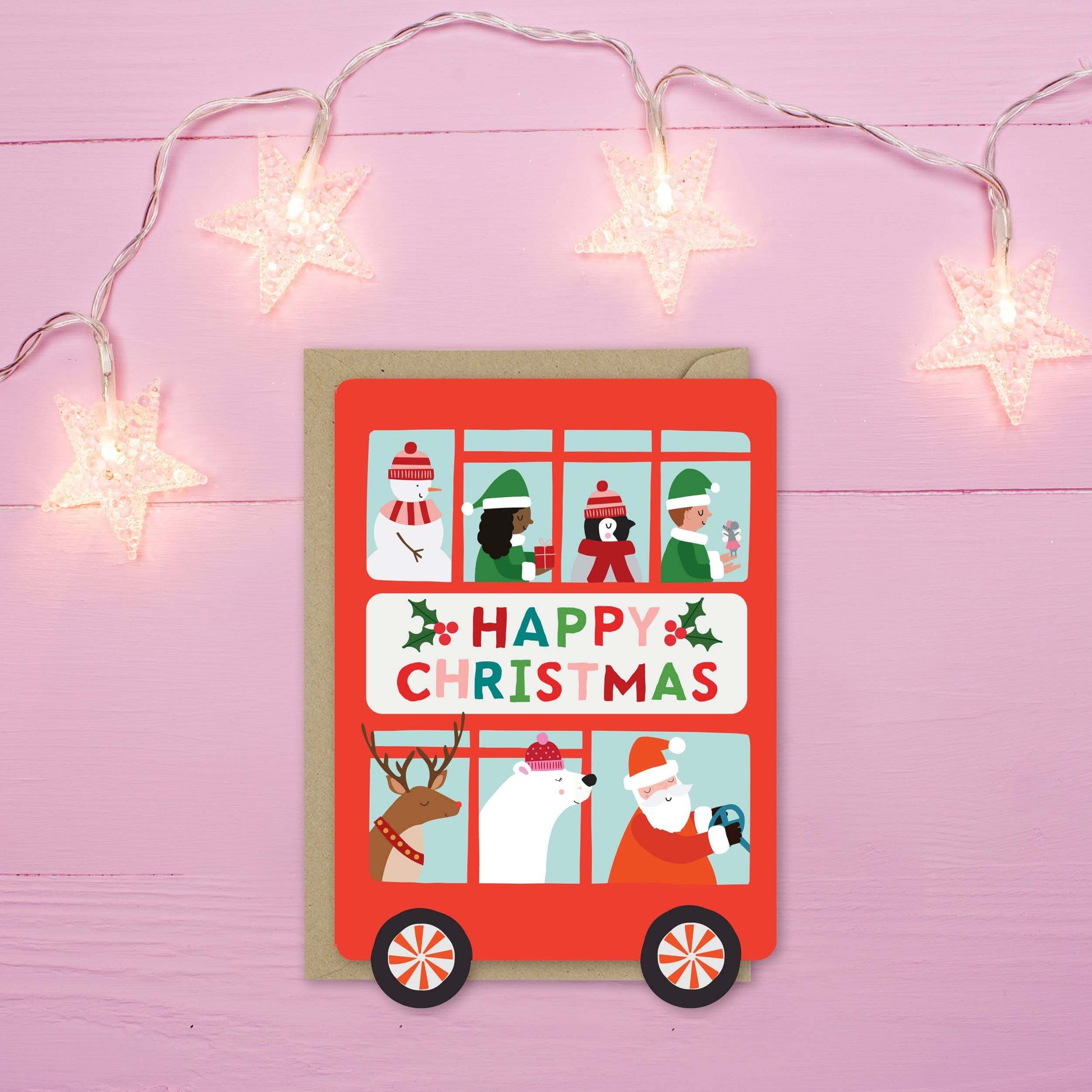 Christmas card with a red bus illustration on a pink background with star lights.