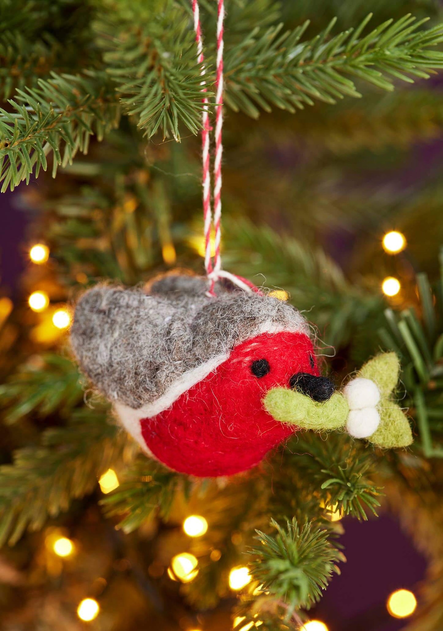 Felt robin decoration hanging on a Christmas tree with blurred lights in the background