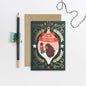 Christmas card with hedgehog design, envelope, pencil, and decorative string on a light gray background