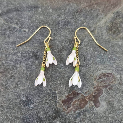 Pair of floral earrings with gold hooks on a stone surface