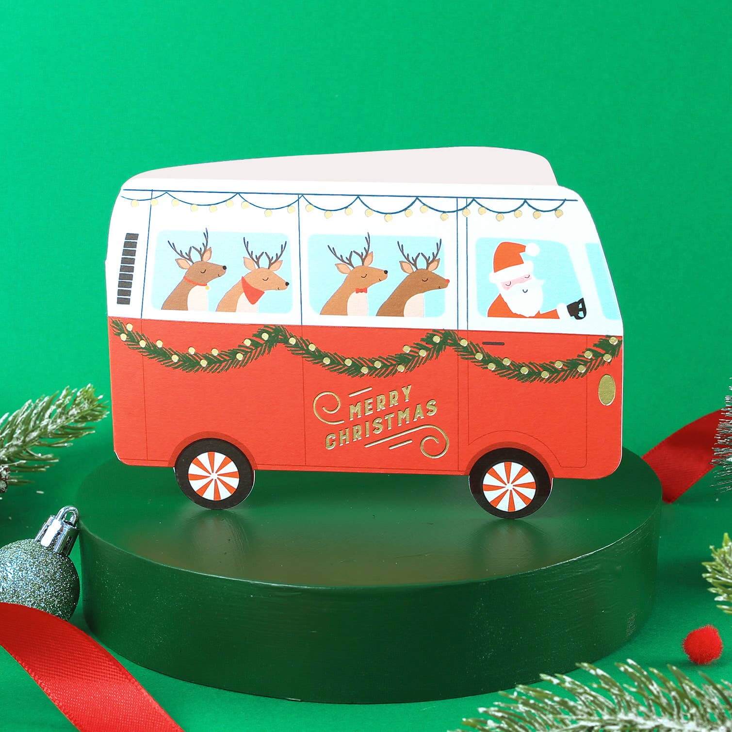 Red Christmas-themed van with reindeer and Santa on a green background