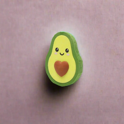 Avocado-shaped eraser with a smiling face and red heart on a white background