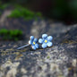 Blue flower-shaped earrings on a textured stone surface