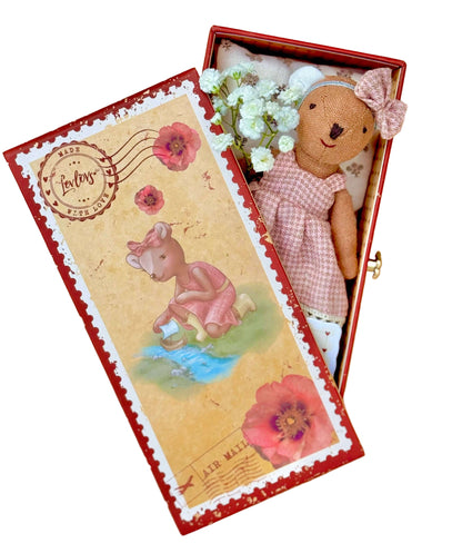 Teddy bear in a decorative box with floral elements on a wooden surface