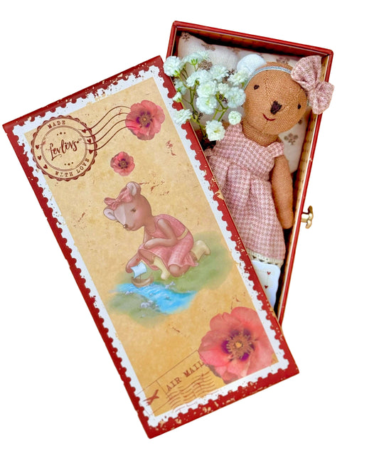 Teddy bear in a decorative box with floral elements on a wooden surface