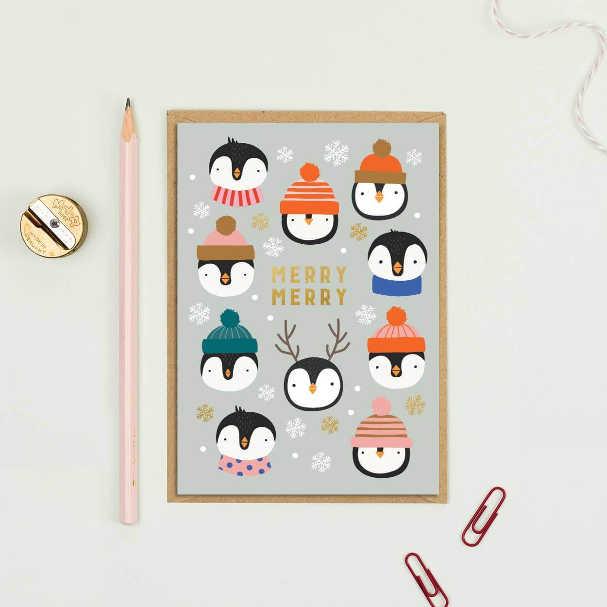 Framed artwork with penguins wearing winter hats on a light gray background