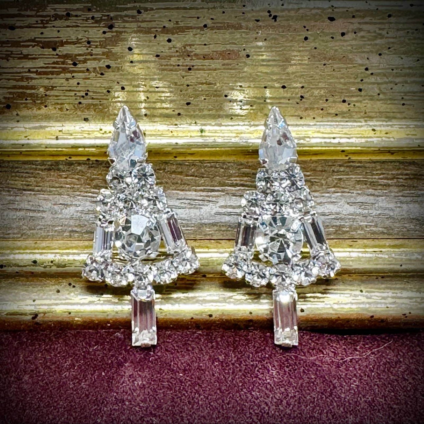 Pair of crystal tree-shaped earrings on a textured surface