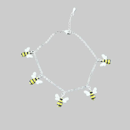 Silver bracelet with bee charms on a gray stone surface