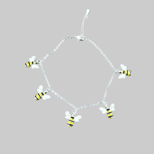 Silver bracelet with bee charms on a gray stone surface